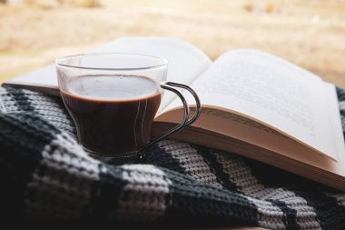 Madrid, İspanya Ekim 12023 örülmüş mavi atkı ya da süveter arkaplanı üzerine açık bir kağıt kitap. Kırsal bir yaşam tarzının rahatlığı. Yavaş yaşam. İçeride ya da doğada edebiyat okumak. Bir kitap, kahve fincanı. 