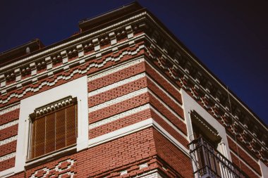 Madrid, İspanya. 7 Ağustos 2023. Kırmızı ve beyaz tuğlalı binanın köşesi. Yazın şehir merkezinde tarihi bir ev. Süslü, güzel bir dış görünüş. Kentsel alandaki yerleşim alanı. 