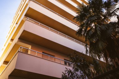 Madrid, İspanya. 20 Kasım 2023 Soyut mimari arka plan ve yüksek palmiye ağaçları arasında beton modern bina. Daire, güneşli bir günde otel balkonları. Şehir manzarası.