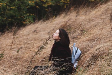 Güz parkındaki, ormandaki ve çayırdaki kuru çimlerin üzerinde güzel, rahat bir kadın oturuyor. Sonbahar mevsiminde doğanın tadını çıkaran bir kız. İnsanlar dışarıda dinleniyor. Dişi gezgin yalnız. Nefes al.