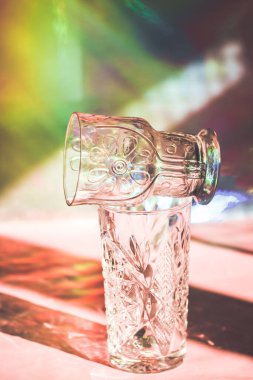 Çok renkli bir arka plan üzerinde bir gölge oluşturan bir gözlük. İçecekler, meyve suları ve 90 'lardan kalma su için nostaljik içecek takımı. Geçmişe dönük hayat güzel sanat.