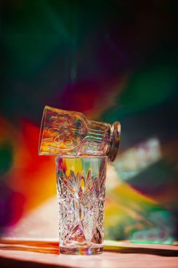 Çok renkli bir arka plan üzerinde bir gölge oluşturan bir gözlük. 90 'lardan kalma nostaljik içecek takımı. Retro natürmort hayat, canlı yüzeye karşı parti dekorasyonu