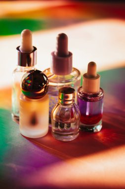 Renkli gökkuşağı gölgelerinde küçük kozmetik pipet şişeleri. Yüz, vücut yağı ürünleri. Masadaki nemlendirici yüz kozmetiği. Güzellik, güzellik uzmanı.