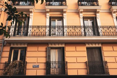 Madrid, İspanya. 1 Aralık 2023 Klasik konut tipi sarı bina cephesi, bir şehir caddesinde balkon. Şehir evleri parçalanmış. İspanyol mimarisi