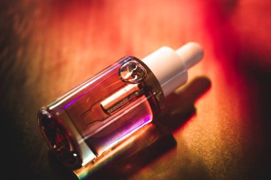 Parlak kırmızı arka planda pipetli cam kozmetik şişesi. Dekoratif kozmetik. Yüz serumu. Moda dergisi tarzı fotoğraf. Gerekli yağ.