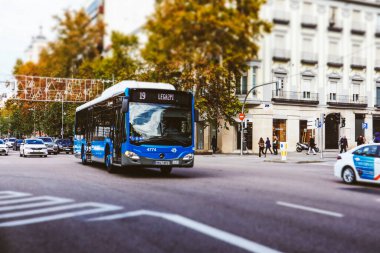 İspanya, Madrid. 19 Kasım 2023 toplu taşıma trafiği, mavi otobüs numarası 19 Legazpi, beyaz taksi şehir trafiğinde ilerliyor. Taşımacılık, otomobiller Eski binalar, mimari