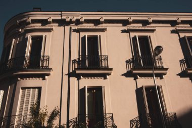 Neoklasik bina cephesi koyu tonda. Güzel bir apartman dairesi cephesi. Penceresinde panjurlar olan balkonlar. Mimari detaylar. Avrupa 'da tipik bir İspanyol evi. 