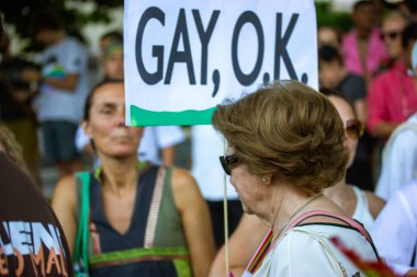 Madrid, Spain July 24, 2022 People with a placard with text Gay Ok walks in a pride month parade. Crowd of people supporting equality, freedom of choice of sexual orientation. Equality support idea.