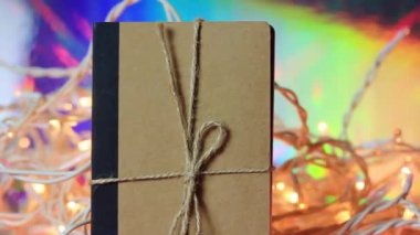 Parıldayan ışıklara karşı Kraft kağıt defteri. Buz çelenkleri. Yılbaşı şenliği, Noel bayramı kutlaması. Sırlar için günlük. Paketlenmiş hediye, hediye