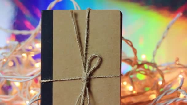 Kraftpapier Notebook Tegen Glinsterende Lichten Ijsbloemenslingers Feestelijk Nieuwjaar Kerstviering Dagboek — Stockvideo