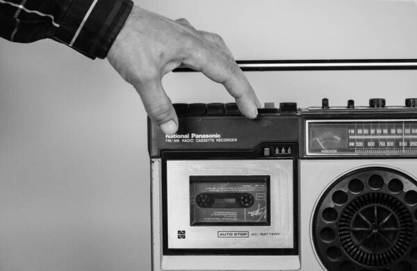 Madrid, Spain. May 2, 2023 A man put music cassette into an old record player. Nostalgia for '90s. Vintage tape recorder Ghetto blaster Music boom box