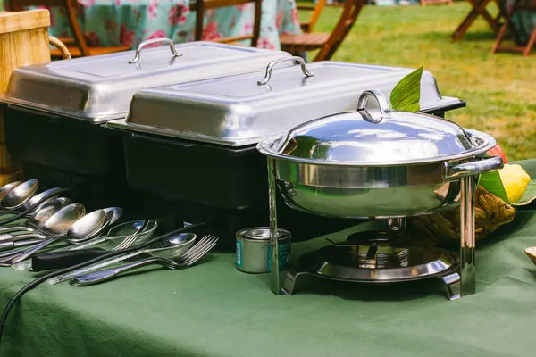 Outdoor kitchen equipment. Preparing food on a barbecue party. Food tray with kitchen utensils, bowls, pots and pans. Backyard banquet. Barbecue party