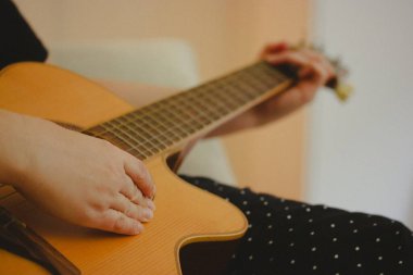 Eski bir klasik akustik gitar çalan yüzü olmayan kadın. Gitaristin elleri yakın plan. Müzik bestelemek, müzik yapmak. Eski renkler.