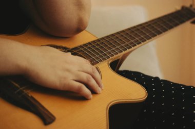 Eski bir klasik akustik gitar çalan yüzü olmayan kadın. Gitaristin elleri yakın plan. Müzik bestelemek, müzik yapmak. Eski renkler.