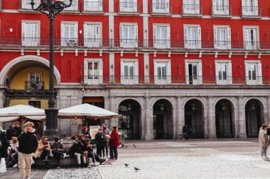 Madrid, İspanya, 27 Şubat 2024 İspanya 'nın başkenti Plaza Mayor' da gezginler. Kırmızı tarihi bina cephesi, tarihi mekan, seyahat yeri