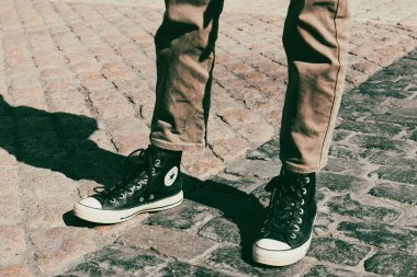 Madrid, İspanya. 1 Şubat 2024 Klasik 90 'lar tarzı Converse marka kadın ayakkabıları. Parke taşlı bir yolda duran bir kız. Klasik stil.