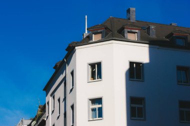 Konutun içi, pencereli ve mavi gökyüzüne karşı gri çatılı bir malikanenin beyaz cephesi. Tarihi merkez mimarisi. 