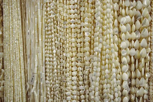 Assortment of white pearls in a fashion store. Pearl background. Female jewelry showcase. Pendants, beads made from natural semi-precious stone beads.