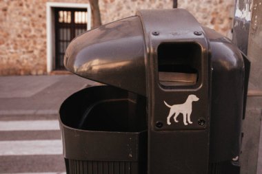 Şehir sokaklarında köpek resmi olan siyah bir vazo. Köpek sahiplerinin yaşam tarzı kavramı. Çöp tenekesi dışarıda. Şehir yaşam tarzı. Çevre sorunu.