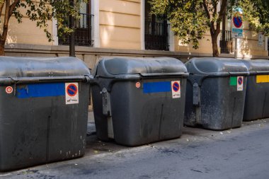 Madrid, İspanya. 1 Mayıs 2023 'te şehir caddesinde çöp konteynırları dolduruldu. Dışarıya çöp bidonları döküldü. Geri dönüşüm konsepti. Gri çöp bidonları. 