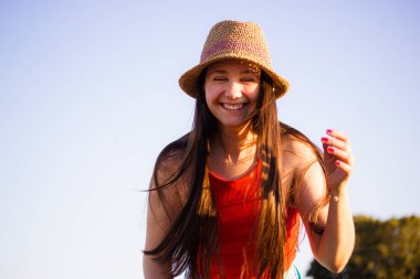 Neşeli genç bir kadın mavi gökyüzüne karşı saman şapkalı bir kadın portresiyle neşeyle gülüyor. Özgür hippilerin keyfi yerinde, mizahı yerinde. Yaz tatili.