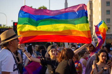 Madrid, İspanya. 3 Temmuz 2022 'de bir grup genç gay geçit töreninde dışarıda eğleniyor. LGBT gökkuşağı bayrakları. Yaz Festivali neşesi. 
