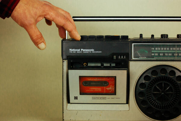 Madrid, Spain. May 2, 2023 A man put music cassette into an old record player. Nostalgia for 90s. Vintage tape recorder Ghetto blaster Music boom box