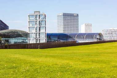 Berlin, Almanya. 2 Ekim 2023 Modern mimari, ayna bina cephesi ve bir iş merkezine giden bir yol. İnsanlar şehir caddesinde yürüyor..