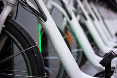 Bicycle parking on city street. Lots of white bikes for rent parked hardly. Environmentally friendly transportation. Ecological e-transport. Details of the bike - spokes, tire wheel macro detail photo