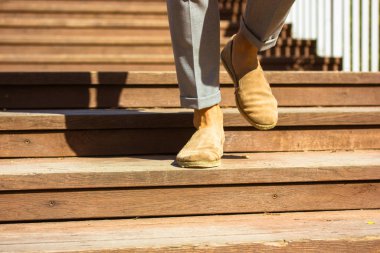 İş adamı ahşap merdivenlerden iniyor. Şık erkek derisi bej kahverengi ayakkabıları. Merdivenlerde erkek bacakları. Şehir halkı yaşam tarzı. 