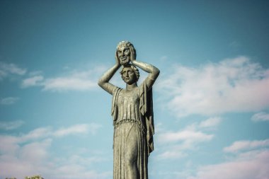Madrid, İspanya. 1 Mayıs 2024 Jacinto Benavente Anıtı. Yüzüne maske takan bir kadın için. Mavi gökyüzüne karşı bronz kadın heykeli. Kadınların güç kavramı,