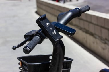 Gidonun üzerinde elektrikli bisikletin şarj levhası olan bir cep telefonu tutucusu. Kentsel bir ortamda taşınmak. Spor ve şehir dışı aktiviteleri. Sepetli bisiklet. Kiralık çevre dostu ulaşım