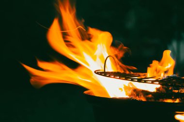 Karanlık arka planda alevler. Rüzgarlı bir gecede yanan güzel odun kömürleri. Doğada yemek pişirmek. Açık havaya hazırlanıyorum. Siyah arkaplanda alevler. 