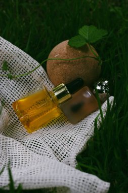 Organik kozmetik ürünler, cam şişeler dolusu kozmetik serumu, yeşil çimenlikteki bez parçasının üzerinde kozmetik ürünler. Yaz aylarında cilt bakımı için kozmetik ürünleri.