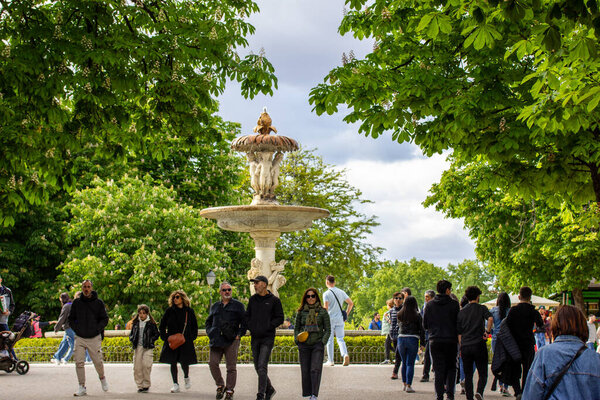 Мадрид, Испания. 2 мая 2024 Толпа людей, идущих по городской улице в весеннем ботаническом саду. Провожу время на улице. Ориентир старинного фонтана. 