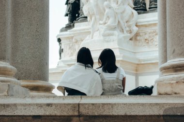 Madrid, İspanya. 1 Haziran 2024 Retiro parkındaki antik bir anıta bakan iki genç kız. Alfonso XII heykellerinin anıtı. 