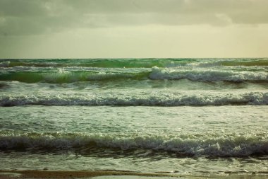 Yeşil dalgalar kıyıya vuruyor. Sakin doğal deniz manzarası. Güzel okyanus dalgaları. Dalgalı su ve kumlu plaj. Zümrüt sular. Sıvı soyut doku.