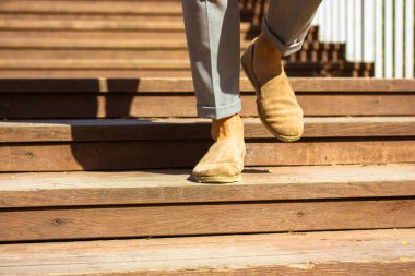 İş adamı ahşap merdivenlerden iniyor. Şık erkek deri bej kahverengi ayakkabılar. Merdivenlerde erkek bacakları. Şehir halkı yaşam tarzı. 