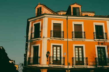 Güneşli ışıkta koyu mavi gökyüzüne karşı eski turuncu bir bina. Sinema filtresi. Evin dış tarafında pencere ve balkon manzaralı bir daire.. 