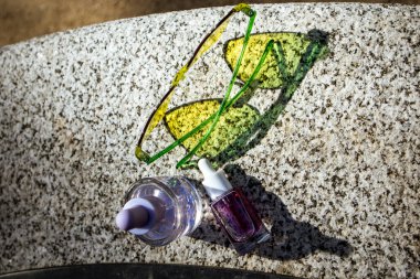 Tropik yaz kozmetik ürünleri. Kozmetik serumu, tropiklerin bereketli yeşilliğine karşı yağ özütü. Cilt bakım ürünleri. Güzellik doğası. Kalp şeklinde güneş gözlükleri..