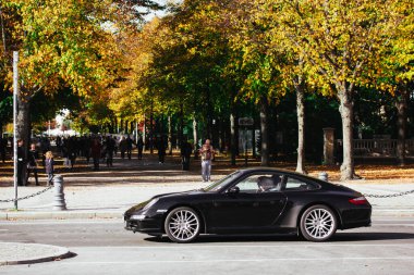 Berlin, Almanya. 3 Ekim 2023. Şehir caddesinde pahalı siyah bir spor araba. Sessiz lüks seyahat konsepti. Porsche 911 spor arabası kullanan zengin bir adam..