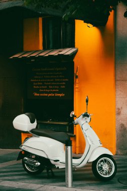 Madrid, İspanya. 11 Temmuz 2024 'te turuncu bina cephesinin yakınındaki eski bir şehir sokağına beyaz bir scooter park etti. Ekolojik şehir ulaşımı. Modern motosiklet.