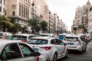Madrid, İspanya 1 Temmuz 2024 Akşamleyin bir trafik sıkışıklığında bir araba akıntısı. Gran Via caddesinde beyaz taksi. Tarihi binalar.