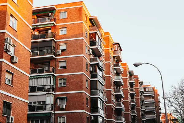 Madrid, İspanya. 1 Mayıs 2024 Bir şehir caddesinde kırmızı tuğlalı bir apartmanın cephesi. Gündüz vakti tipik İspanyol evi. Emlak.