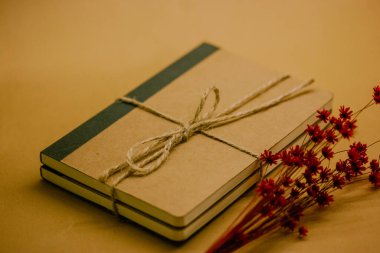Kraft vintage doğal, basit kahverengi karton defter kahverengi masanın üzerinde. Ekolojik kurdeleli kağıt günlük ve kırmızı küçük çiçek buketi. Yaz anıları. 