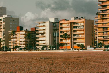 Gandia, İspanya. 20 Temmuz 2024 Kumlu sahildeki apartman binalarının cepheleri. Bir tatil köyünde konut. İspanyol mimarisi