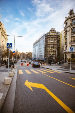 Madrid, İspanya. 1 Temmuz 2024 Asfalt yolu, sürücüler için sarı işaretli, sola sarı ok, şehirde yaya geçidi zebrası. Modern binalar. 