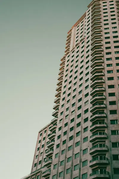 stock image Skyscraper view from bottom to top against grey sky. Tall multi-story residential apartment building in urban city environment. Cityscape architecture