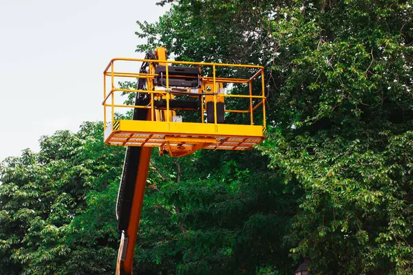 stock image High yellow lift crane with platform for garden works, trees care. Cutting tree on a high. Hydraulic ramp. Remove branches and twig. Gardening work.