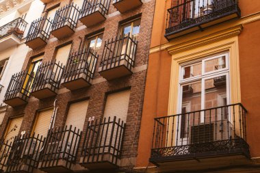 Madrid, İspanya Temmuz 12024 farklı mimari tarzların karşıtlığı. Kahverengi tuğla kaplı bina, eski bir caddede sarı eski bir balkon.